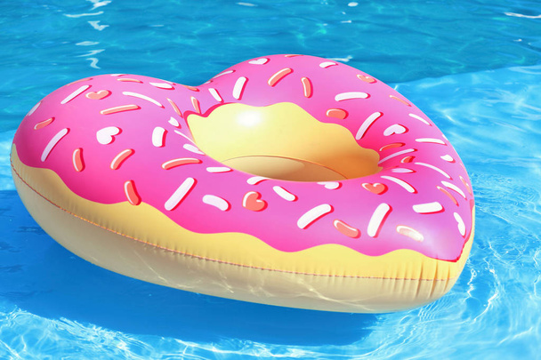 Heart shaped inflatable heart floating in swimming pool on sunny day - Foto, Imagem