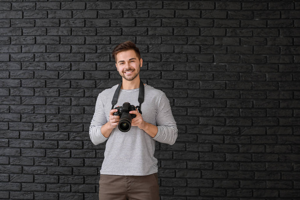 Young male photographer on dark background - Foto, Imagem