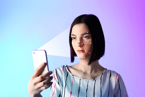 Mujer joven con teléfono móvil que utiliza el sistema de reconocimiento facial para la protección de datos
 - Foto, Imagen
