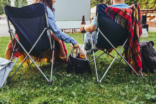 para siedzi w obozie-krzesła w parku miejskim patrząc film na zewnątrz na wolnym powietrzu kino - Zdjęcie, obraz