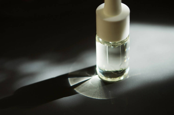 Cosmetic or medical glass bottle with pipette. Skin care concept. Natural hard light, deep shadows. - Image - Φωτογραφία, εικόνα