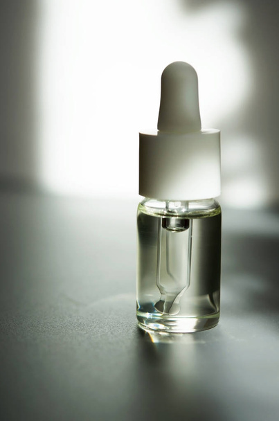 Cosmetic or medical glass bottle with pipette. Skin care concept. Natural hard light, deep shadows. - Image - Fotó, kép