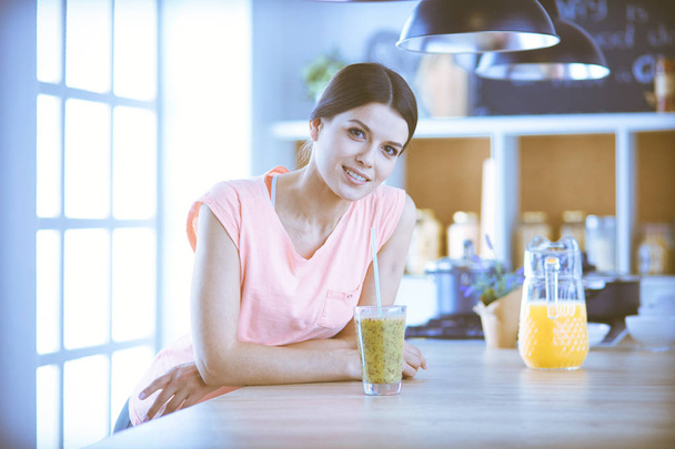 Young woman sitting a table in the kitchen - Foto, Imagen