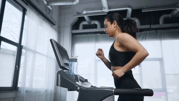 Schöne junge Sportlerin läuft auf Laufband im Sportzentrum - Filmmaterial, Video