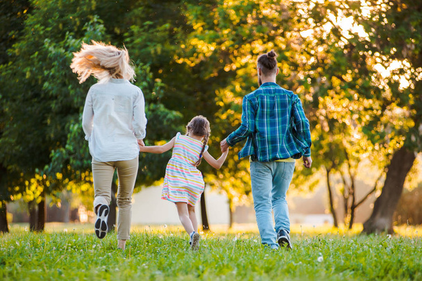 Счастливая молодая семья проводит время вместе на зеленой природе. - Фото, изображение