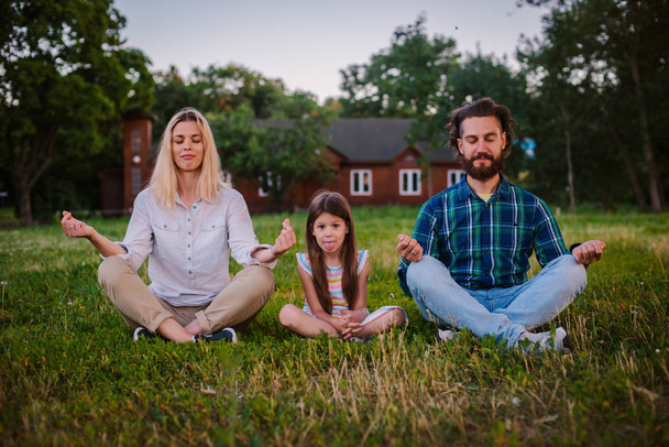 Mãe pai e filha criança meditar juntos na posição Lotus ao ar livre. - Foto, Imagem