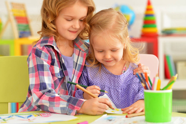 Śliczne małe dziewczynki, siedzi przy stole i rysunek z ołówków w ich pokoju - Zdjęcie, obraz
