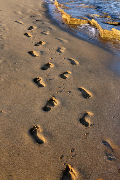 voetafdrukken in het zand op het strand aan de Middellandse Zeekust in het noorden van de staat Israël  - Foto, afbeelding