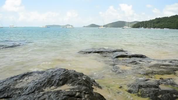 Scenérie pobřeží na Ao Yon Beach, vlny se vymyly na skalách v nízkém úhlu pohledu, Andamanské moře s jachtou pod zamračený modrý nebe v Phuketu, Thajsko. - Záběry, video