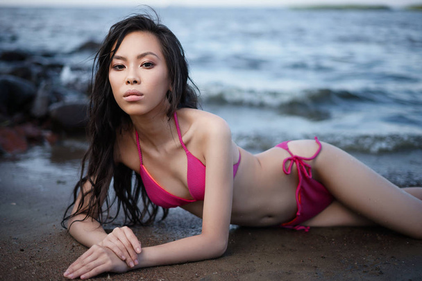 2枚ピンクの水着で若いリーンかわいいアジアの女の子は海岸でリラックス - 写真・画像