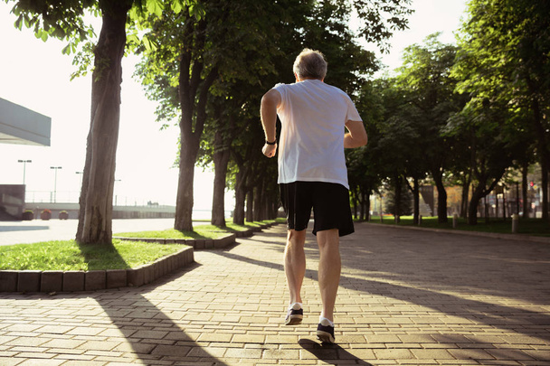 Senior man as runner with armband or fitness tracker at the citys street - Fotó, kép