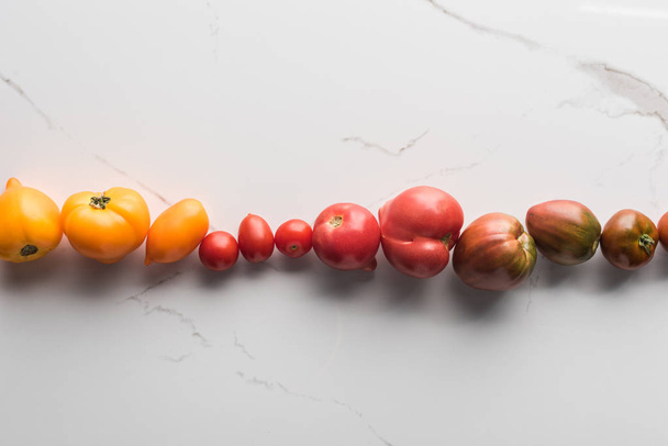flat lay with colorful tomatoes on marble surface  - Foto, Bild