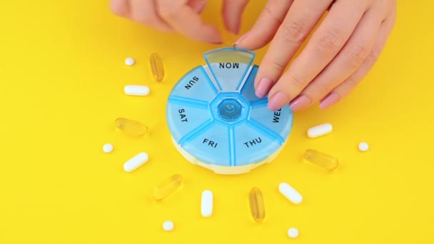 mujer joven pone la medicina en una caja de pastillas, fondo amarillo
 - Imágenes, Vídeo
