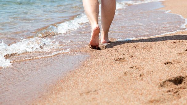 Sahilde çıplak ayakların yakın çekim. Suyun kenarında kumda yürüyorum. Tatil ve seyahat konsepti. Kadın bacakları. Kozmetik ve vücut bakımı. Plaj seyahat - kum plajda kadın bacaklar - Fotoğraf, Görsel