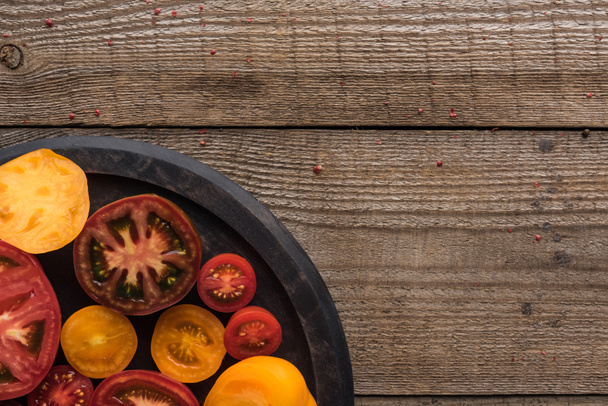 top view of red and yellow tomatoes on pizza pan on wooden table  - Foto, afbeelding