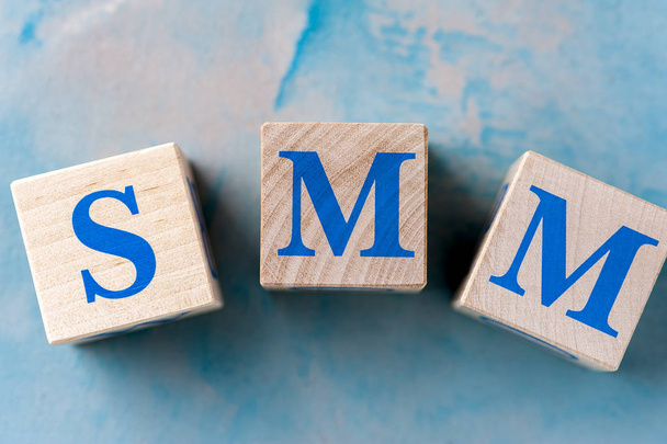 Wooden cubes with word SMM on blue table. - Fotografie, Obrázek