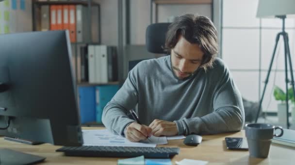 Handsome Long Haired Entrepreneur Sitting at His Desk in the Office Works on Desktop Computer, Working with Documents, Correcting Charts, Drawing Graphs, Statistic and Updating Company Strategy - Filmati, video