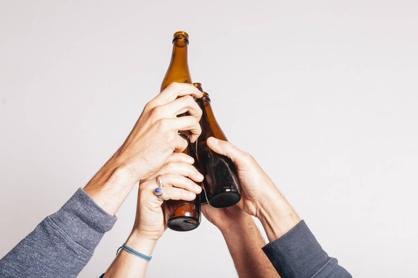 hands holding a bottle of beers and toasting up  - Photo, image