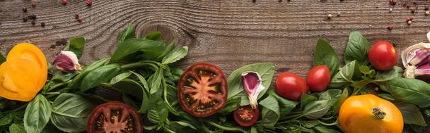 panoramic shot of spinach, sliced tomatoes, garlic and scattered pepper on wooden table - Foto, Imagen
