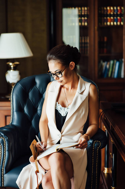 Very beautiful business woman sits in an office chair and plans her business for the future - Foto, Bild