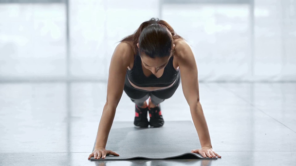 young sportswoman doing push ups on fitness mat in sports center - Footage, Video