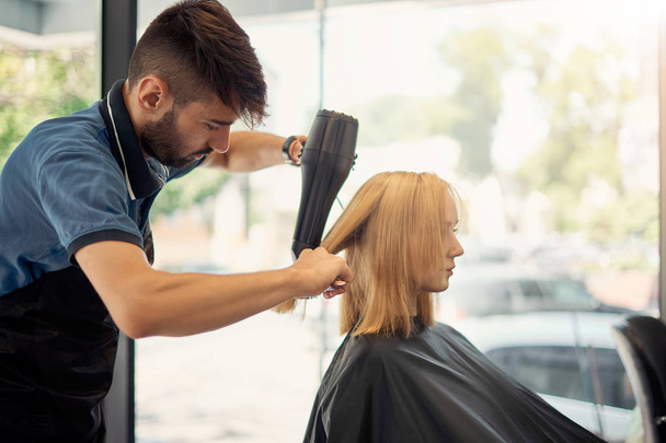 coiffeur masculin coiffant une belle blonde
  - Photo, image