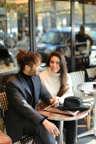 Hombre afroamericano y mujer caucásica sentados en la cafetería de la calle y hablando
. - Foto, imagen