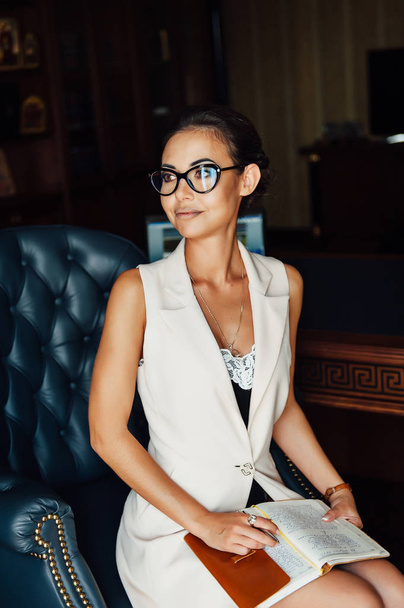 Very beautiful business woman sits in an office chair and plans her business for the future - 写真・画像