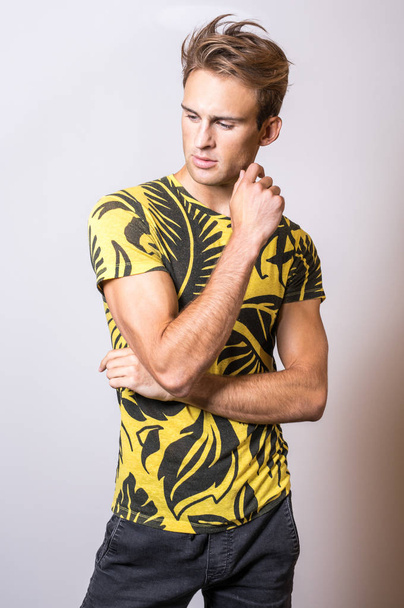 Elegant young handsome man in yellow T-shirt. Studio portrait. - Zdjęcie, obraz