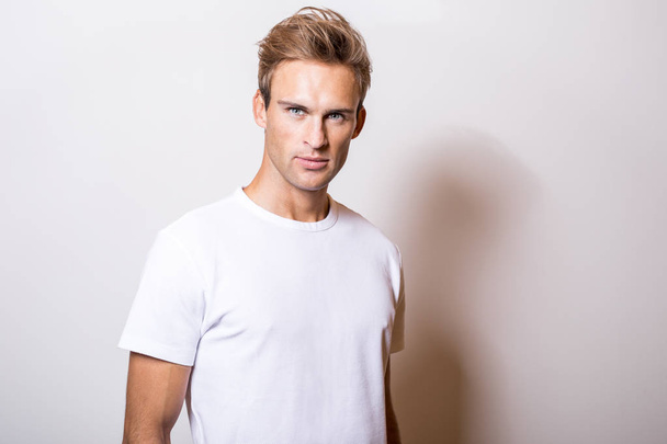 Elegant young handsome man in white T-shirt. Studio portrait. - Valokuva, kuva