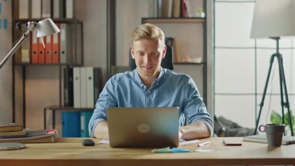 Handsome Blonde Businessman Sitting at His Desk in the Office Works on a Laptop. Creative Entrepreneur Using Computer Working on Software Unicorn Startup Project. Student Writing Paper for University - 映像、動画