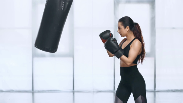 красивая юная спортсменка тренируется с боксерской грушей в спорткомплексе
 - Кадры, видео