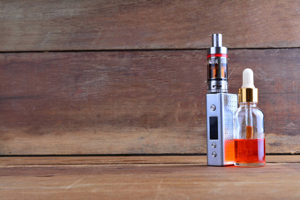 E-cigarette or vaping device with liquid on wooden background - Photo, Image