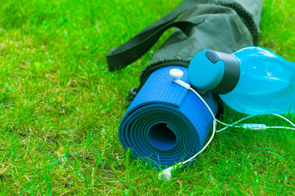 eine Flasche Wasser auf einer Yogamatte auf frischem grünen Gras. das Konzept des Lernens und der Erholung. Sport und Gesundheit.. Kopierraum. - Foto, Bild