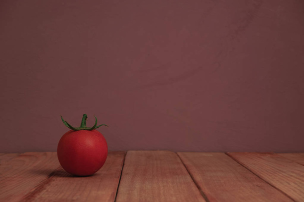 Vers alleen tomaat op een rode houten tafel mooie paarse achtergrond. - Foto, afbeelding