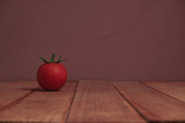 Tuore yksin tomaatti punaisella puupöydällä kaunis violetti tausta
. - Valokuva, kuva
