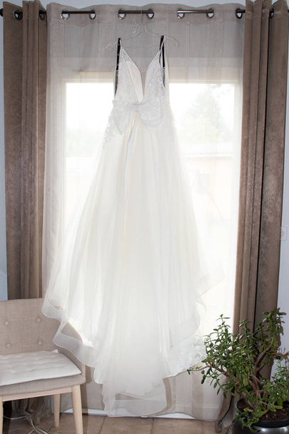 abito da sposa bianco appeso a una finestra
 - Foto, immagini