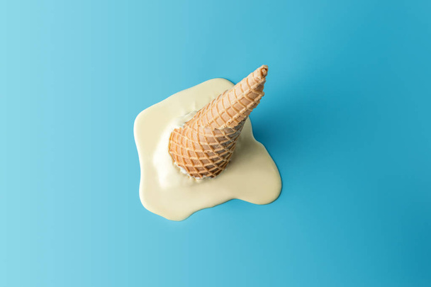 Melted ice cream with ice cream cone on pastel blue background.  - Foto, immagini