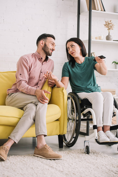 attractive disabled woman talking with handsome boyfriend while watching tv together at home - Foto, Imagem