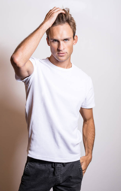 Elegant young handsome man in white T-shirt. Studio portrait. - Foto, Imagen
