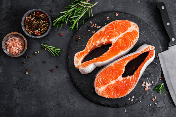 Bistecche di pesce salmone crudo su sfondo nero
 - Foto, immagini