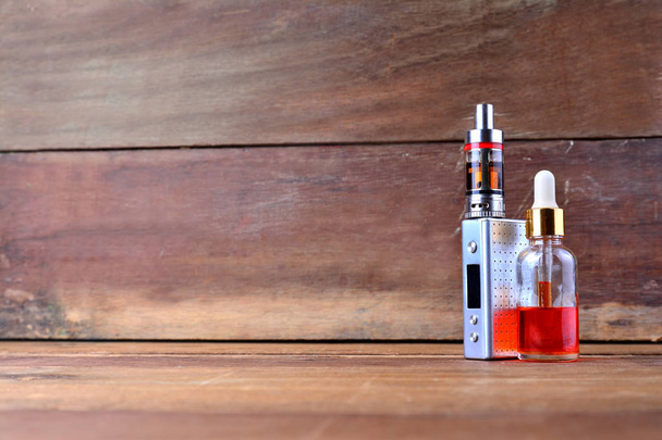 E-cigareta nebo vaping zařízení s kapalinou na dřevěné pozadí - Fotografie, Obrázek