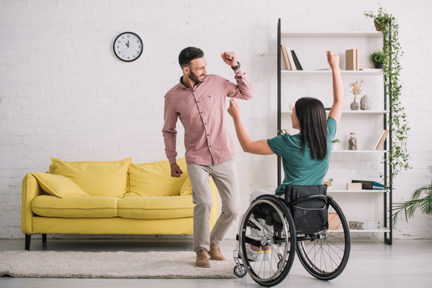 vista posteriore della giovane donna disabile in sedia a rotelle che balla con il fidanzato felice
 - Foto, immagini