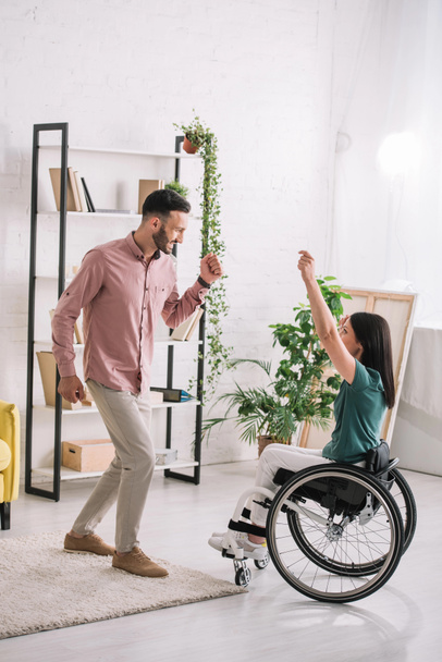 giovane donna disabile sulla sedia a rotelle che balla con il bel fidanzato a casa
 - Foto, immagini
