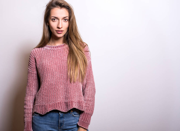 Young model woman in sweater pose in studio. - 写真・画像