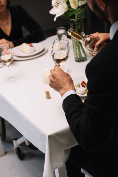 engelli kız arkadaşı ile romantik bir akşam yemeği yerken cam beyaz şarap döken adam kırpılmış görünümü - Fotoğraf, Görsel