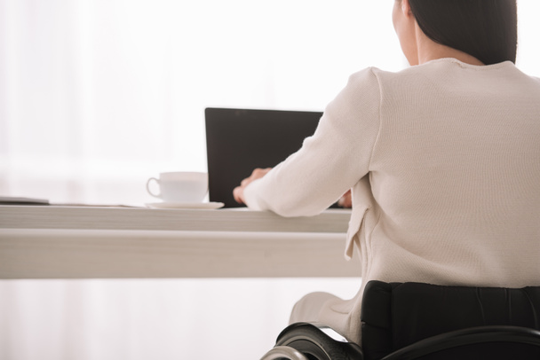 vue arrière d'une femme d'affaires handicapée utilisant un ordinateur portable alors qu'elle était assise au bureau
 - Photo, image