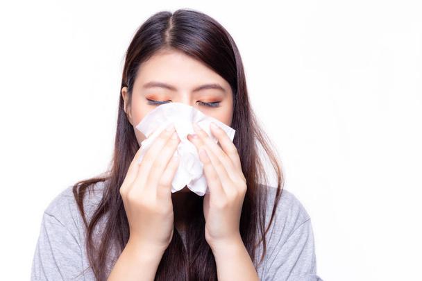Beautiful asian woman has a cold or flu. She feel sick and dizzy. Pretty girl blowing nose by using tissue paper. She has nasal congestion or stuffed nose and running nose. She get sinusitis disease - Фото, изображение