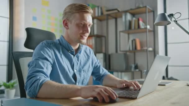 Jóképű szőke üzletember ül az íróasztalánál az irodában egy laptopon dolgozik. Creative Entrepreneur Számítógép használata Szoftver egyszarvú Startup Project. Student Writing Papír az egyetem számára - Felvétel, videó