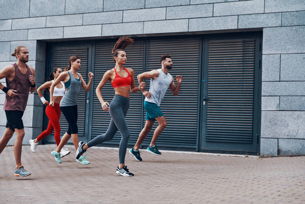 Group of young people in sports clothing running in city street  - Foto, immagini